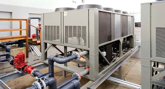 Industrial chiller installation with pumps, connected piping and mechanical equipment for HVAC and district cooling applications